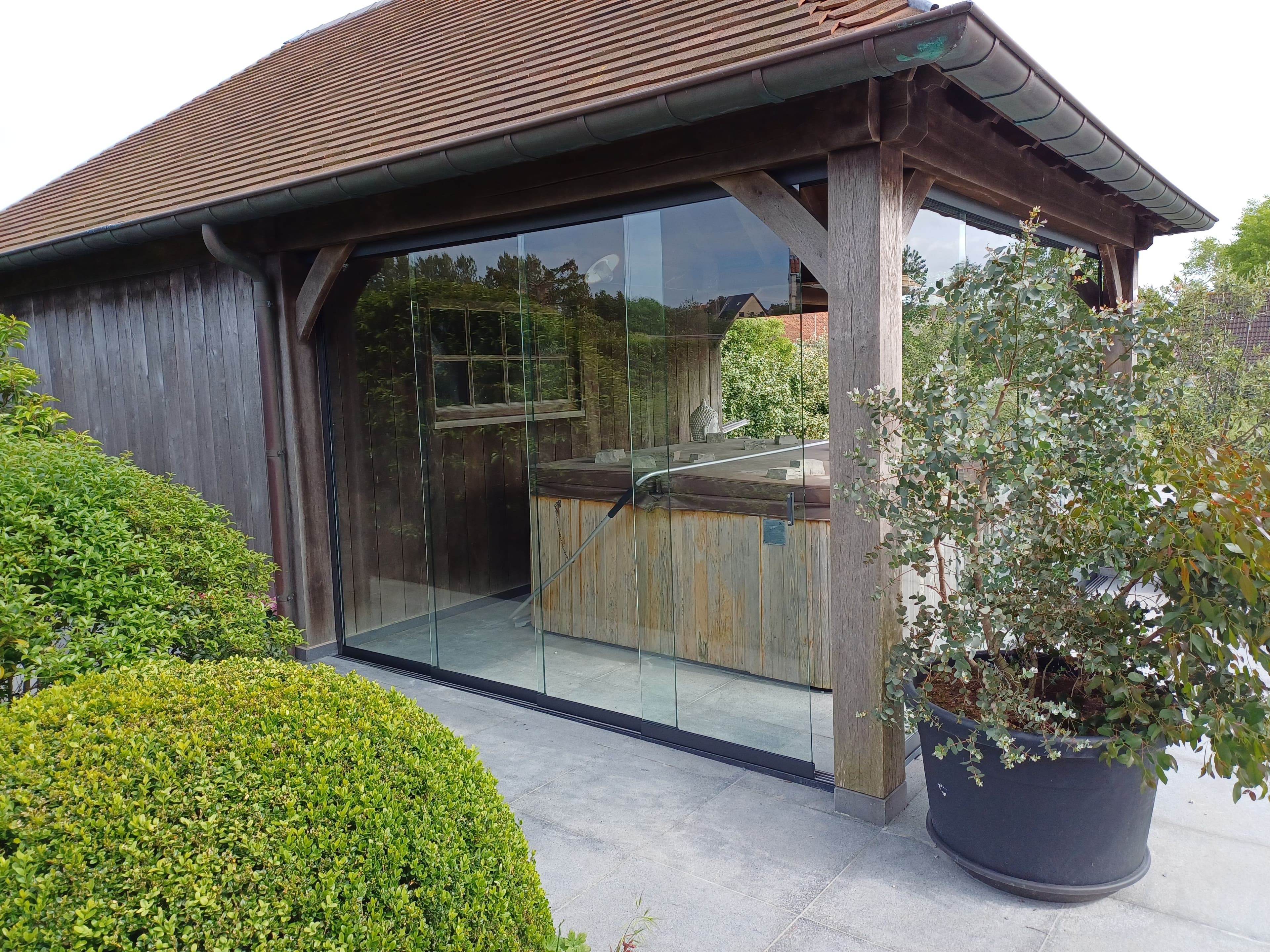 glazen schuifwanden onder houten overkapping ter bescherming van jacuzzi